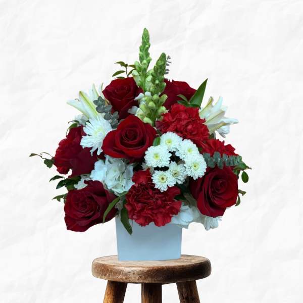 Red roses and white flowers arranged in a light blue box on a stool