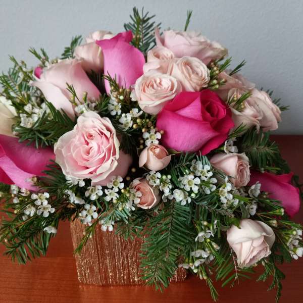 Pink and blush roses arranged in a gold square vase
