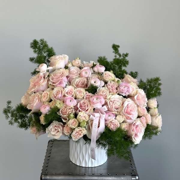 Large bouquet of pale pink roses and ranunculus in a white vase