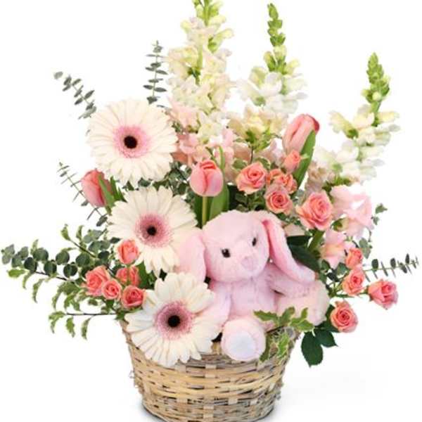 Basket arrangement with pink flowers and a plush bunny