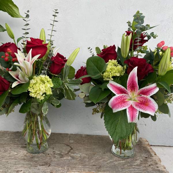 Two bouquets of red roses and pink lilies in glass vases