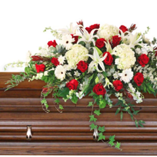 Red and white floral spray on a wooden casket