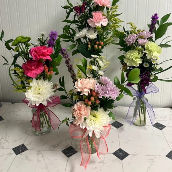 Three mixed flower bouquets in glass vases with ribbon bows