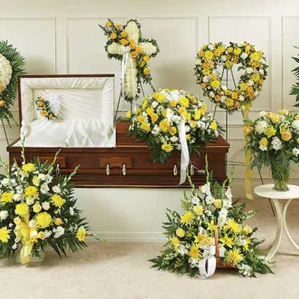 Yellow and white funeral floral tributes arranged around a casket
