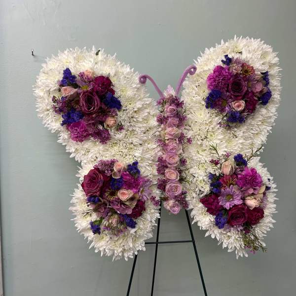 Butterfly-shaped floral arrangement with white and purple flowers on a stand