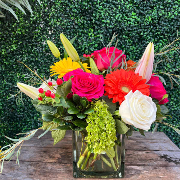 Mixed bouquet of roses, gerbera daisies, lilies, and hydrangea in a glass vase