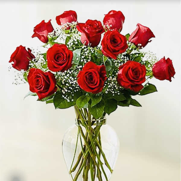 Red roses arranged in a clear glass vase with baby's breath