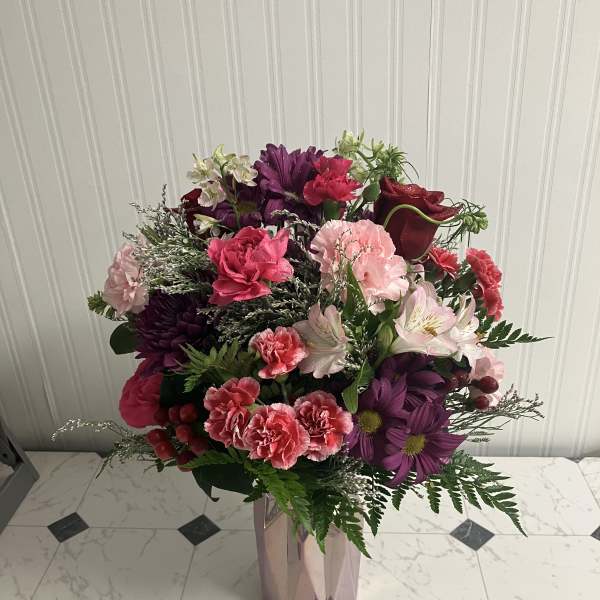 Mixed bouquet of pink, purple, and white flowers in a faceted vase
