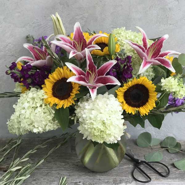 Bouquet of pink lilies, sunflowers, and white hydrangeas in a vase