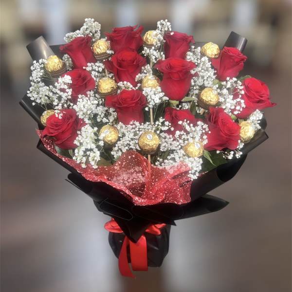 Bouquet of red roses with gold-wrapped chocolates and white baby's breath