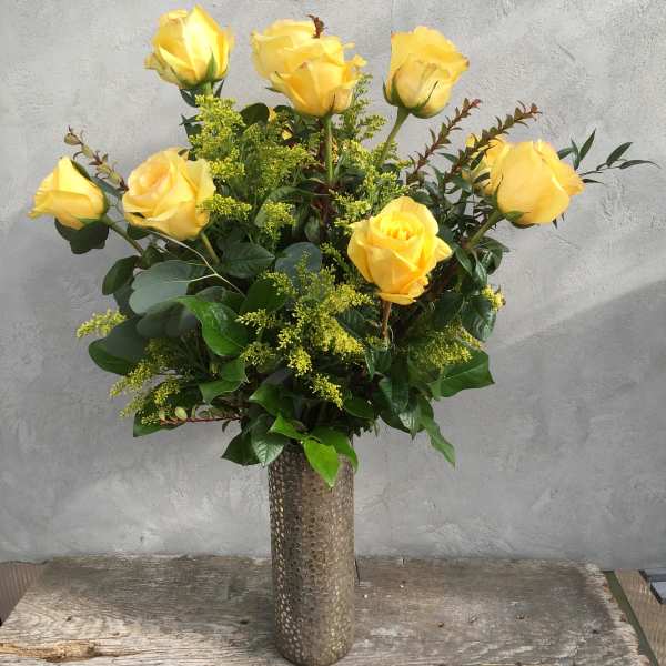 Yellow roses arranged in a tall textured vase
