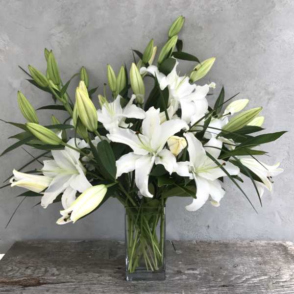 White lilies arranged in a clear glass vase
