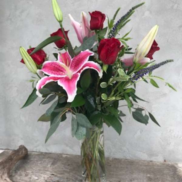 Bouquet of red roses and pink lilies in a glass vase