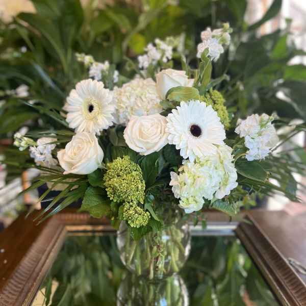 White roses and gerbera daisies arranged in a glass vase