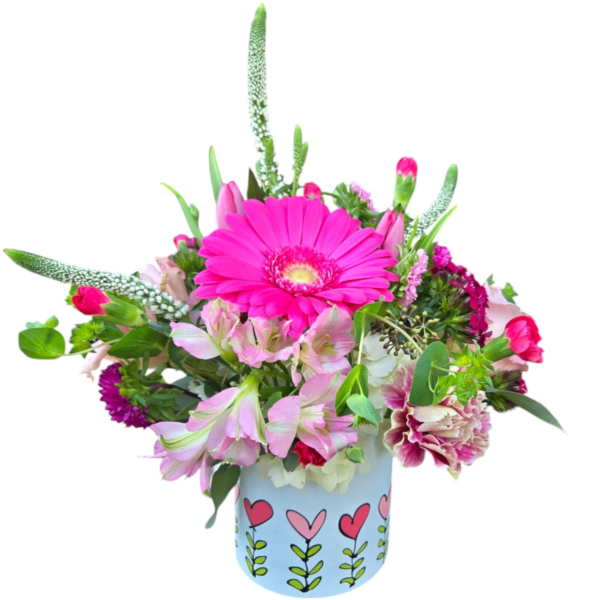 Pink gerbera daisy arrangement with mixed pink blooms in a white heart-pattern vase