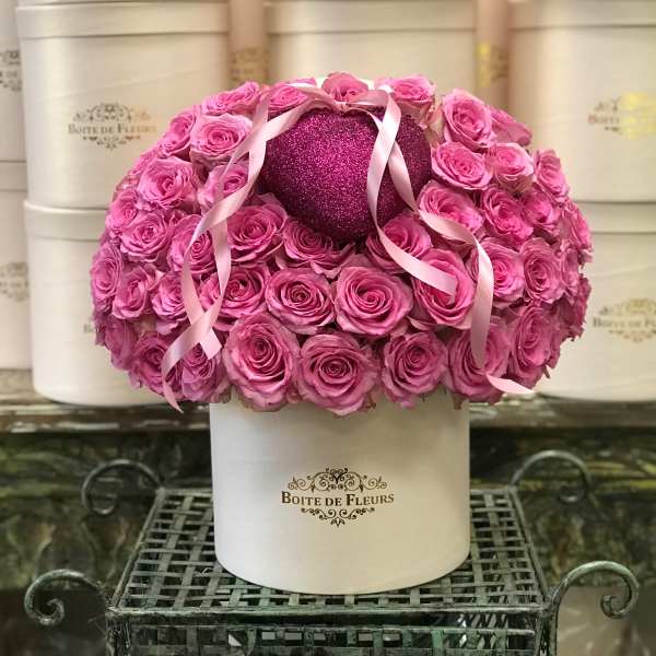 Pink roses arranged around a glittery heart in a white hat box