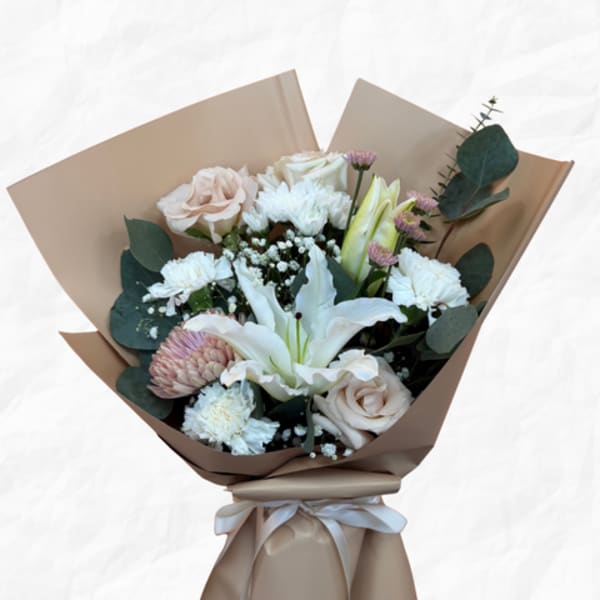 Bouquet of white and blush flowers wrapped in tan paper