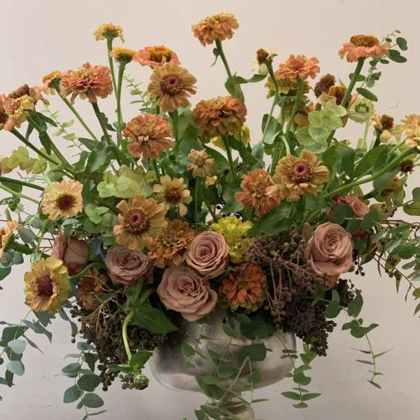 Mixed peach and pink flowers in a silver pedestal vase