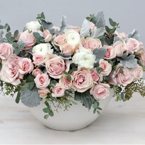 Pink and white rose arrangement in a white vase