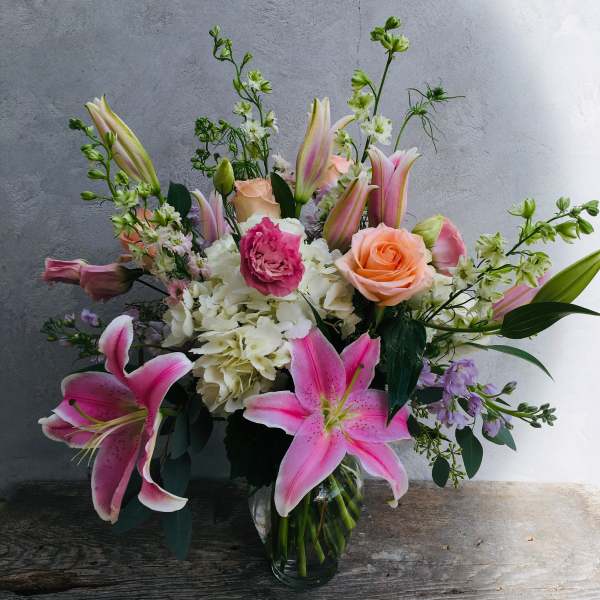 Pink lilies and roses arranged in a clear glass vase