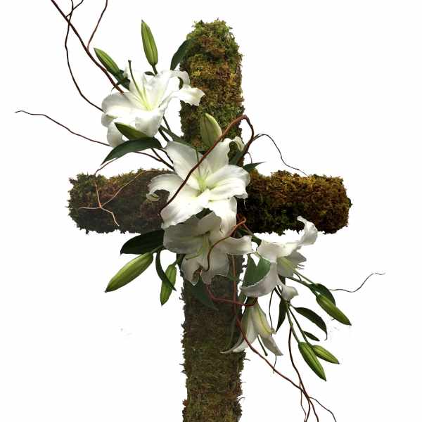 White lilies arranged on a moss-covered cross