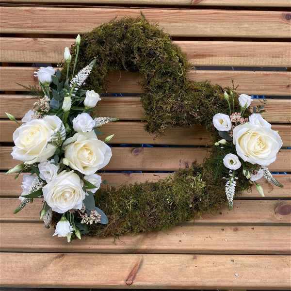 White rose floral wreath with moss on a wooden slat background