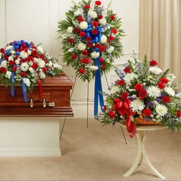 Casket surrounded by red, white, and blue funeral flower sprays