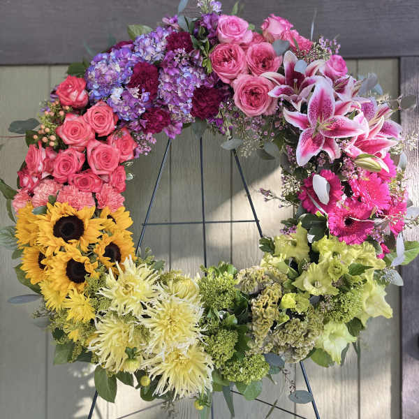 Colorful floral wreath on a stand with roses, lilies, sunflowers, and chrysanthemums