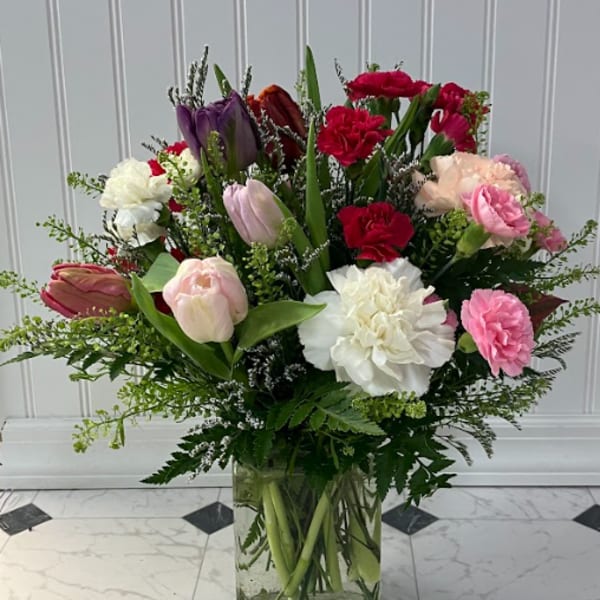 Mixed bouquet of tulips and carnations in a glass vase