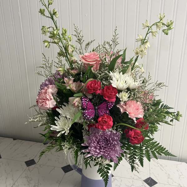 Mixed bouquet in a lavender vase with pink, white, and purple flowers