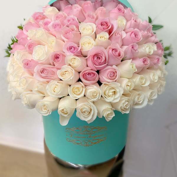 Pink and white roses arranged in a turquoise hat box