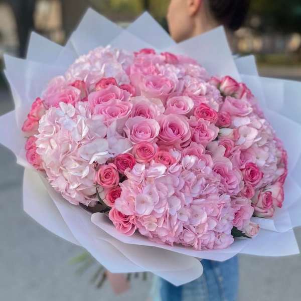Large bouquet of pink roses and hydrangeas wrapped in white paper
