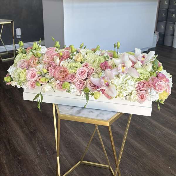 Long pastel floral arrangement in a white box with pink roses and white orchids