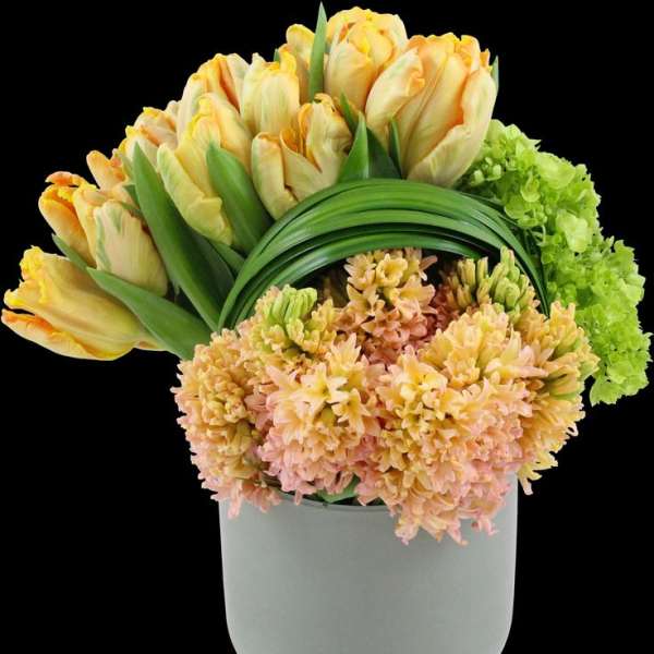 Yellow tulips and peach flowers arranged in a white vase