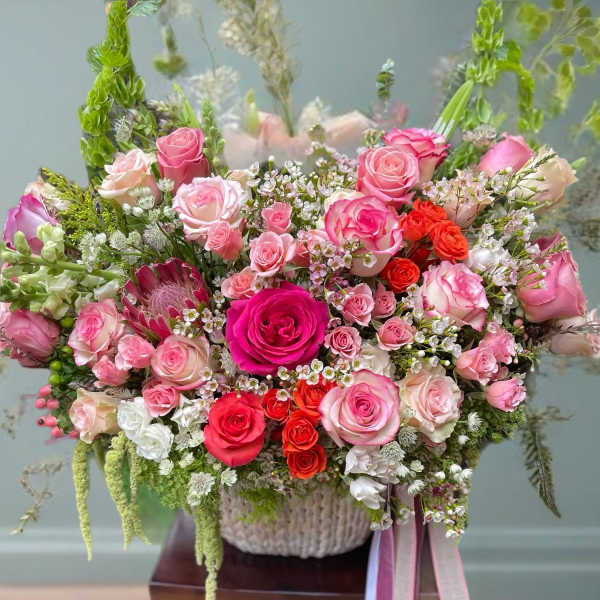 Large bouquet of pink and red roses in a woven basket