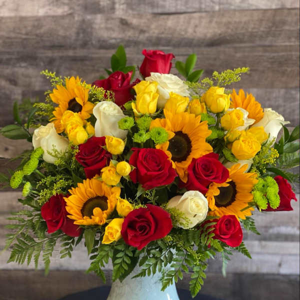 Bouquet of red, yellow, and white roses with sunflowers in a white vase