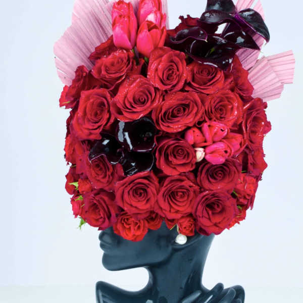 Red rose bouquet arranged in a black mannequin bust vase
