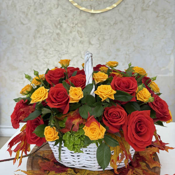 Basket of red and yellow roses with autumn leaves
