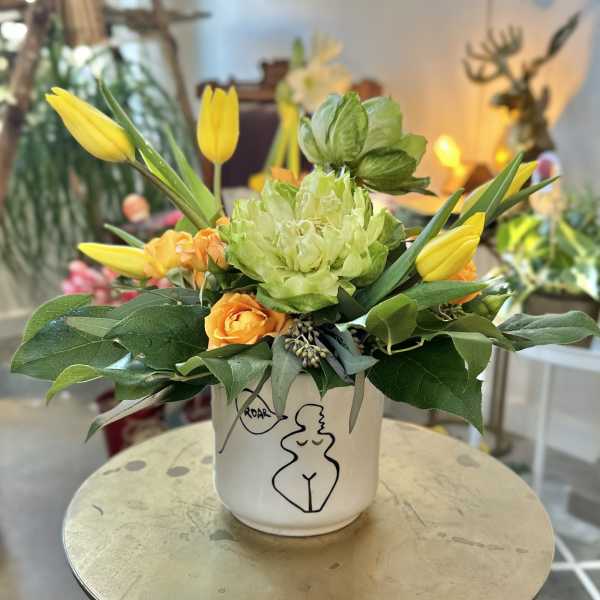 Yellow tulips and orange roses in a white ceramic vase
