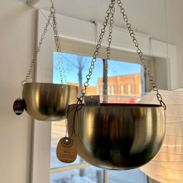Two gold hanging planters suspended from chains indoors