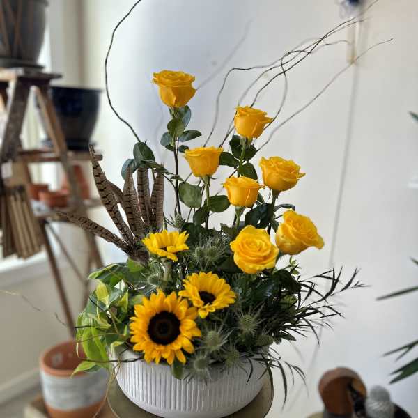 Yellow roses and sunflowers in a white ribbed vase