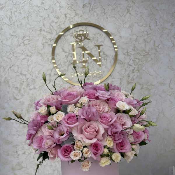 Pink and cream roses arranged in a round pink box