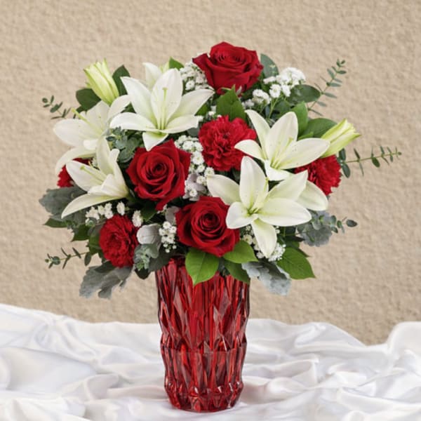 Red roses and white lilies in a red glass vase