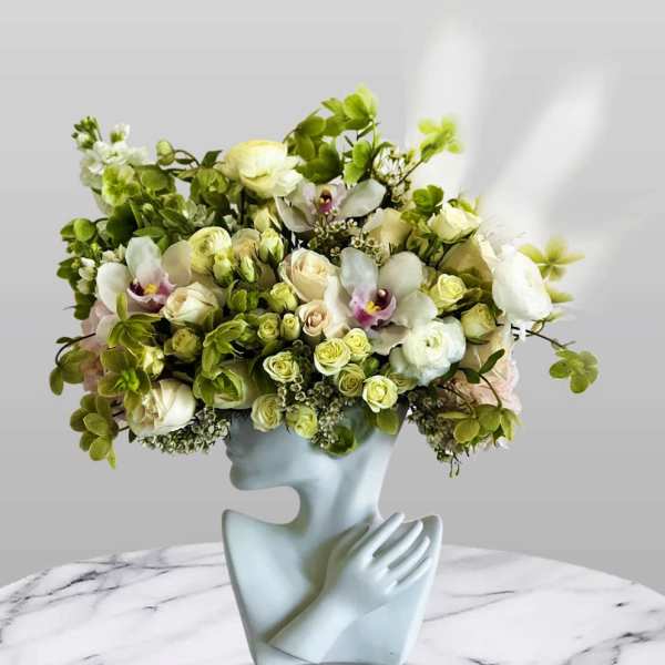 Bouquet of white and pale green flowers in a sculptural face vase