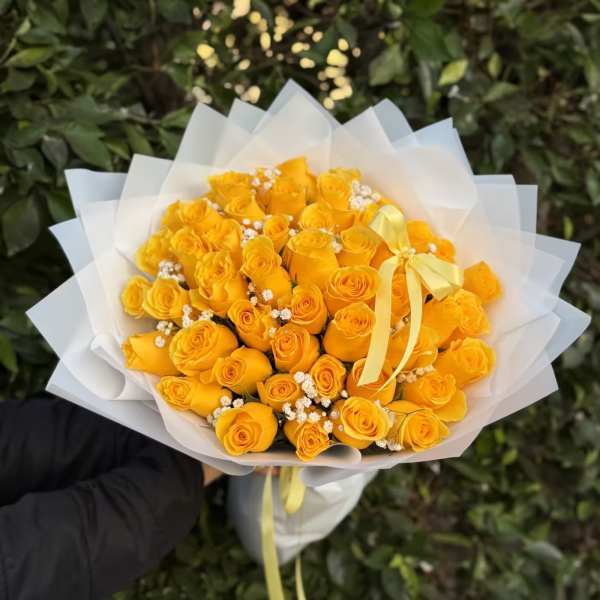 Bouquet of yellow roses wrapped in white paper with a ribbon