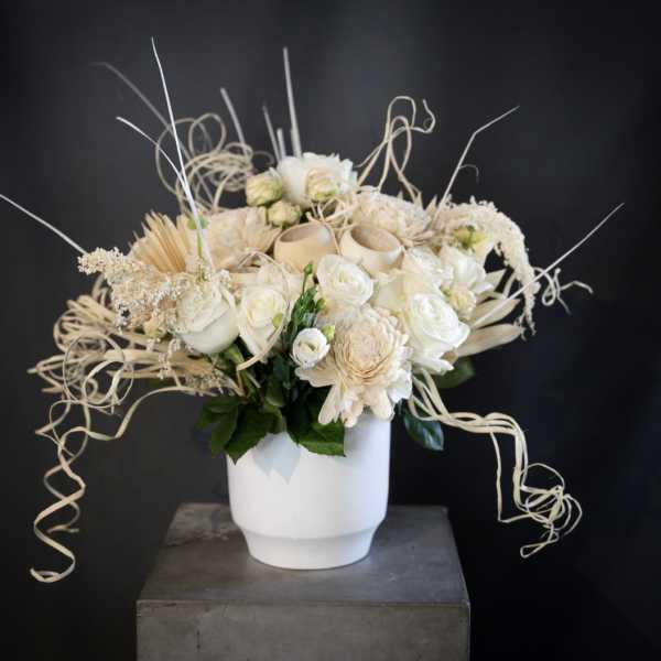 Cream floral arrangement in a white vase with curly decorative accents