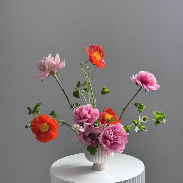 Pink and orange flowers arranged in a white vase
