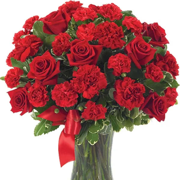 Red roses and carnations in a clear glass vase with a red ribbon
