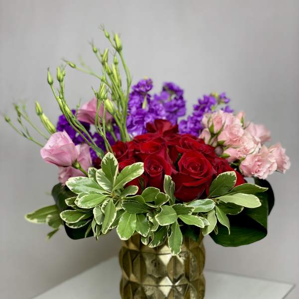 Red roses with pink and purple flowers in a gold vase