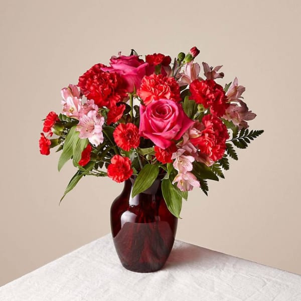 Pink and red flower bouquet in a dark glass vase